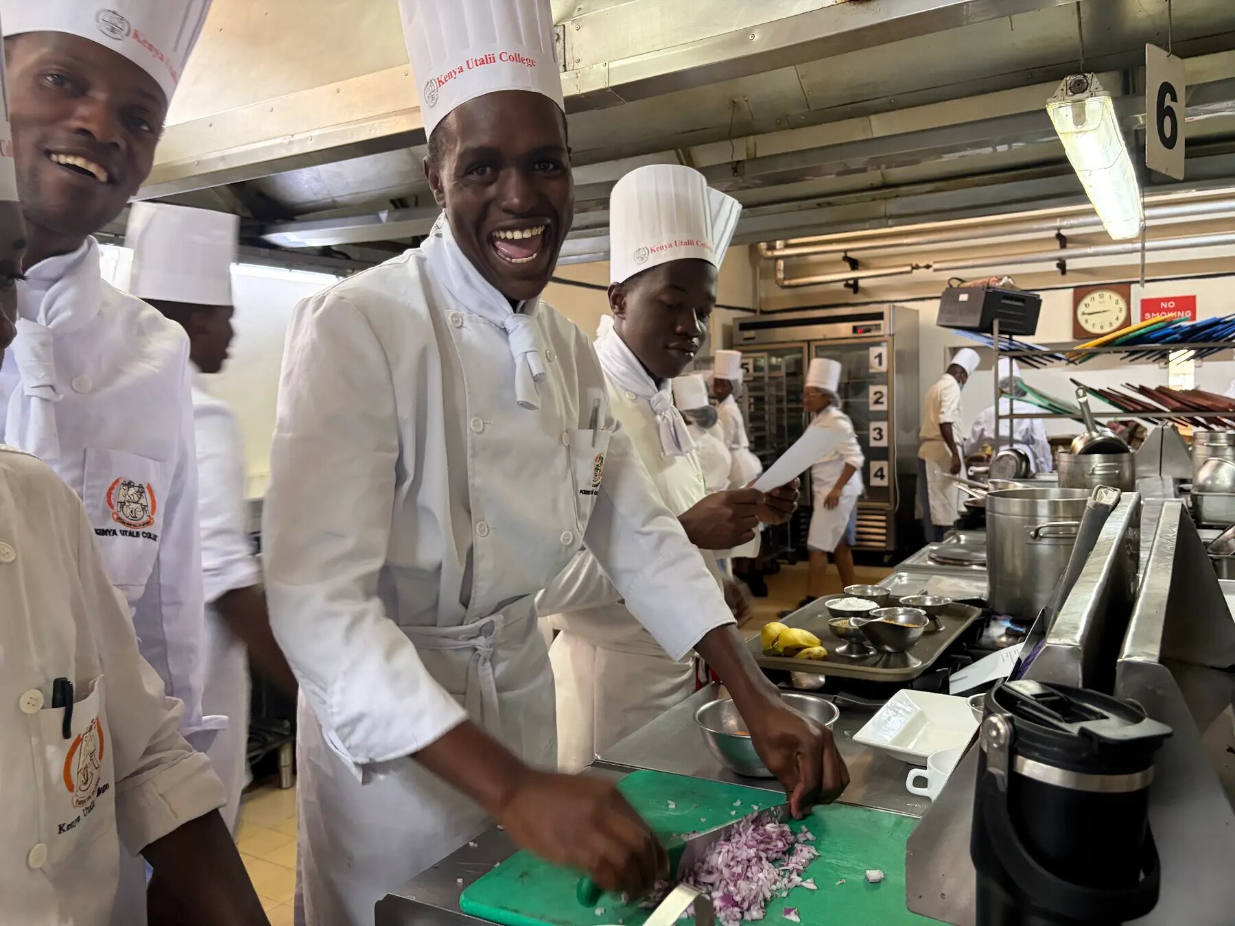 Chef laughing while preparing onions in a professional kitchen