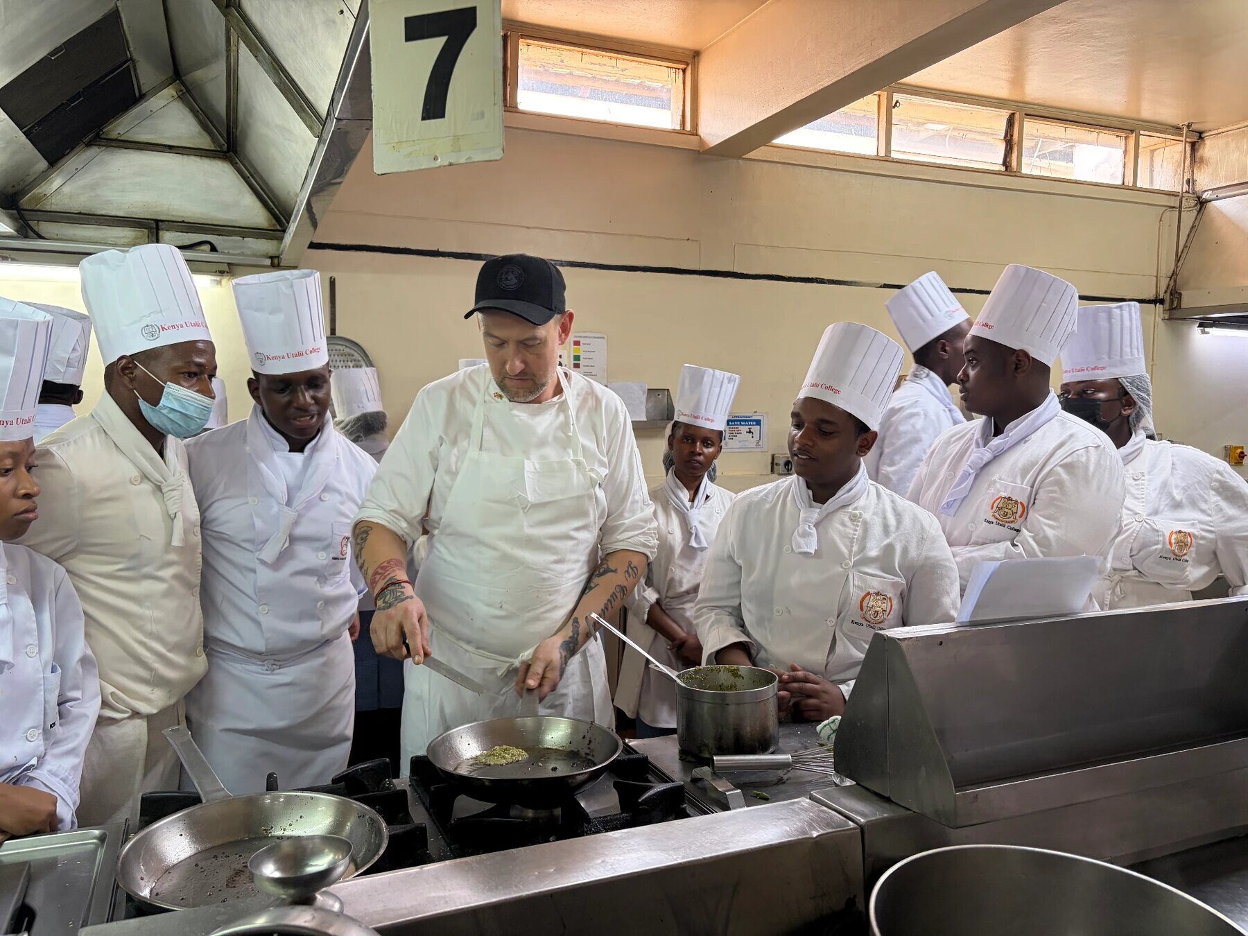 Cooking technique being demonstrated in a pan to a group in a teaching kitchen