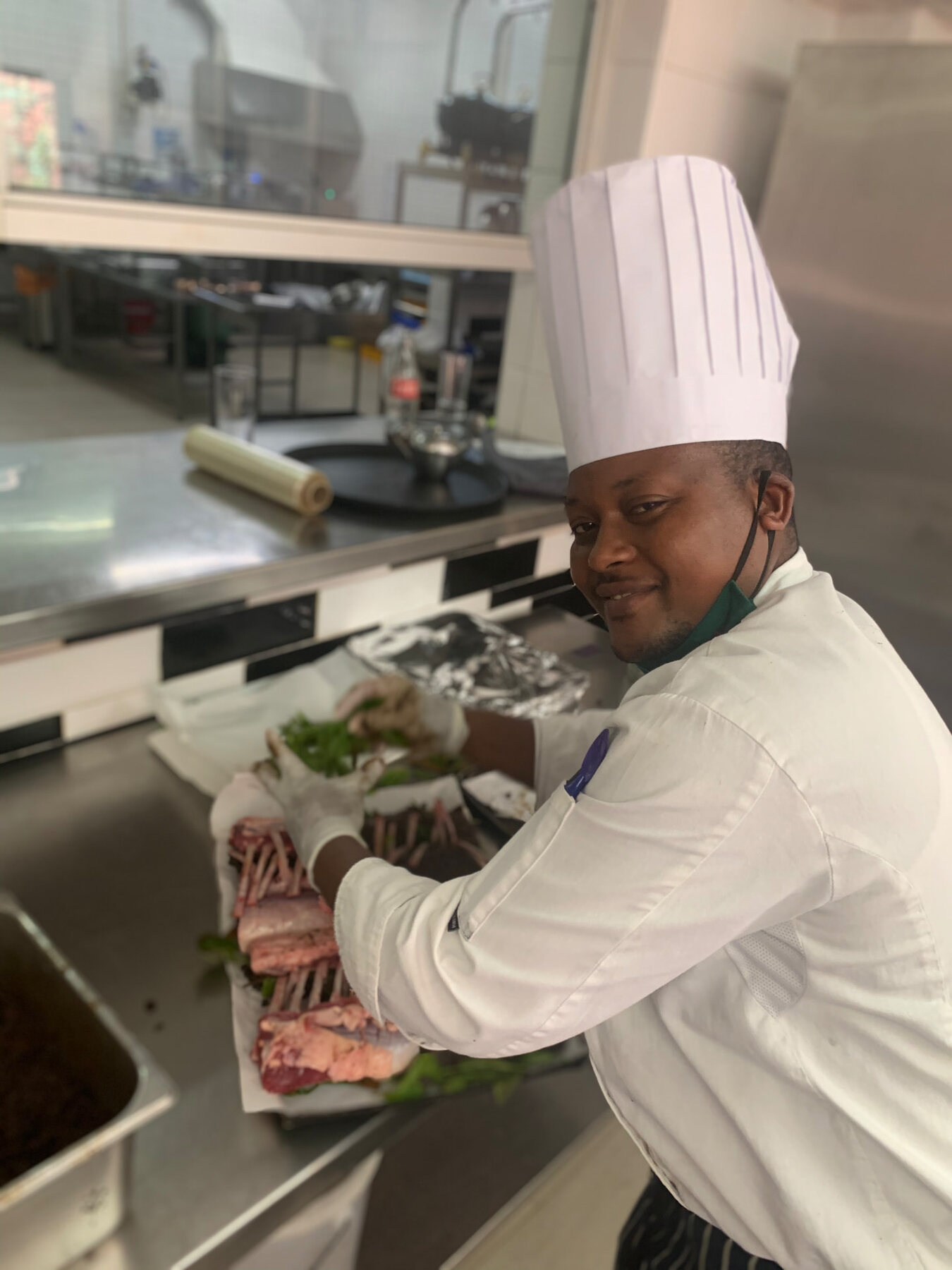 Chef presenting prepared cuts of meat on a stainless steel counter